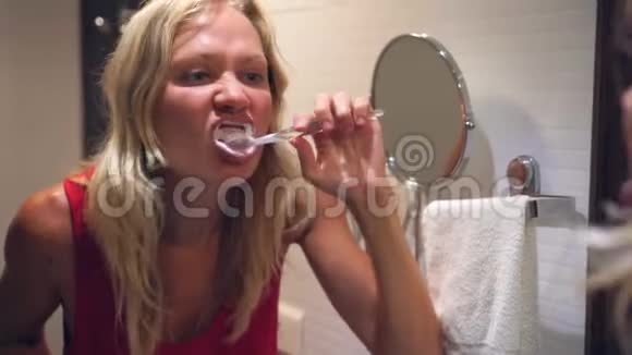 一个女人正在镜子前的浴室里刷牙视频的预览图