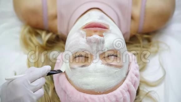 美容师用奶油给女人做面膜一个美容诊所的女孩视频的预览图