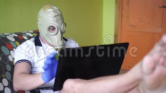 一个戴着呼吸器或防毒面具的人在家里用笔记本电脑工作预防感染视频的预览图