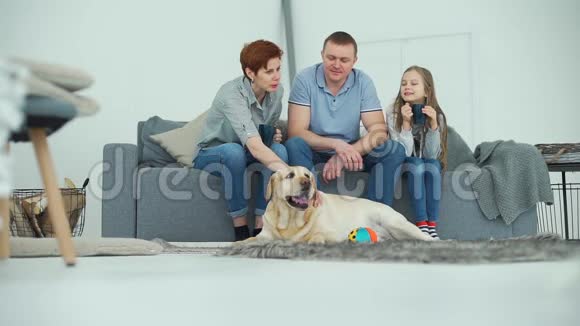 一家三口坐在沙发和宠物狗上视频的预览图