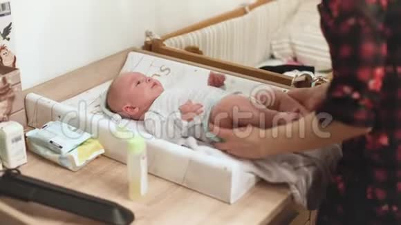 婴儿在换桌子移动的手和腿当他的母亲准备他的衣服视频的预览图