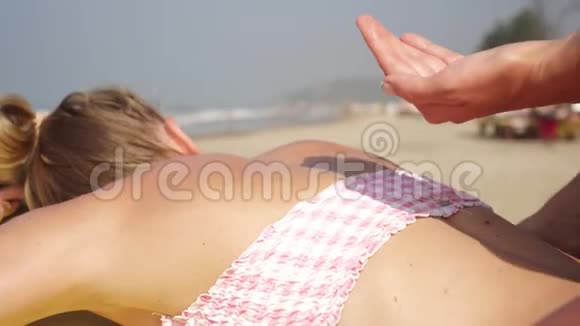 女人把防晒霜涂在女孩的皮肤上性感女人在海滩上晒日光浴视频的预览图