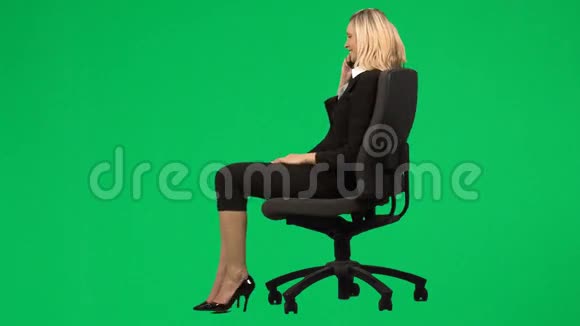 女商人坐在椅子上对着绿色屏幕播放电话视频的预览图