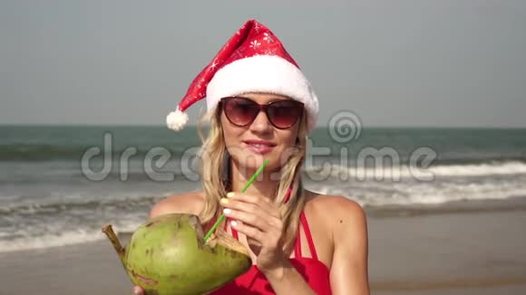 一个女人戴着椰子戴着圣诞帽在大海背景上的肖像视频的预览图