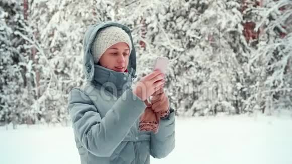 可爱的微笑女孩用手机在户外聊天冬天学生模特视频的预览图