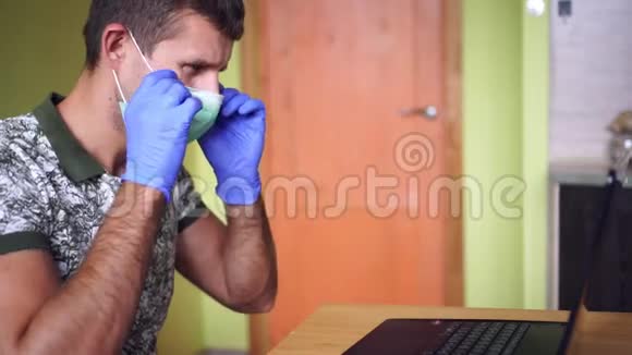 戴着医用口罩和手套的商人在家里工作手提电脑视频的预览图
