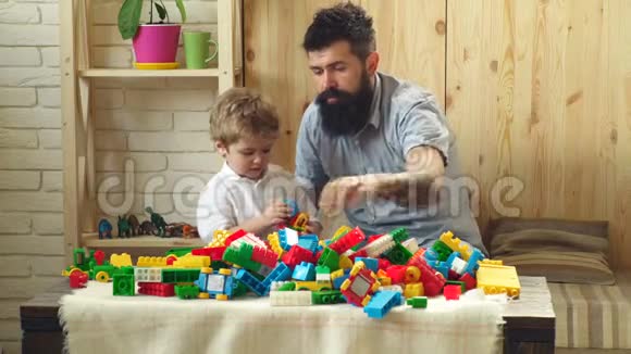 家庭和童年的概念男人和男孩一起在木墙背景上玩耍爸爸和孩子搭塑料积木视频的预览图