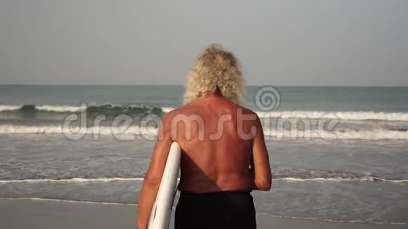 有冲浪的成熟男人的肖像带着冲浪板在海滩上的祖父视频的预览图