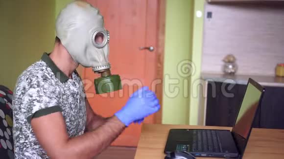 一个戴防毒面具或呼吸器的人正在笔记本电脑上工作冠状病毒和远程工作视频的预览图