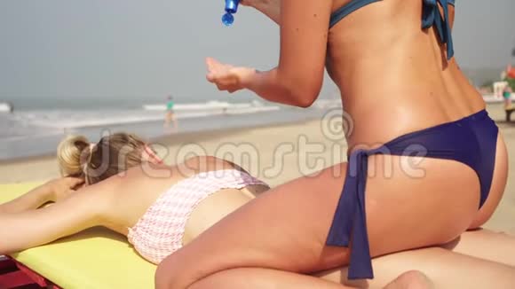 女朋友在海滩上用防晒霜涂抹他们的皮肤海滩上性感的女人视频的预览图