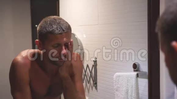 一个昏昏欲睡的年轻人早上在浴室的镜子前打哈欠视频的预览图