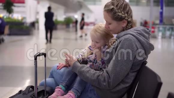 乘客在机场使用智能手机在机场候机楼有孩子的女人视频的预览图
