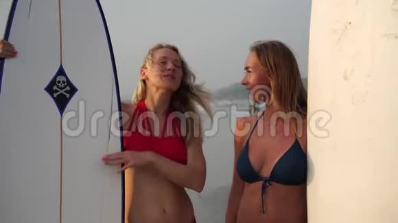 两个年轻漂亮的女人在大海的背景下冲浪视频的预览图