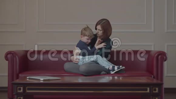 年轻的30岁的母亲在失望的时候安慰她的小儿子孩子在妈妈膝盖上哭女人拥抱男孩视频的预览图