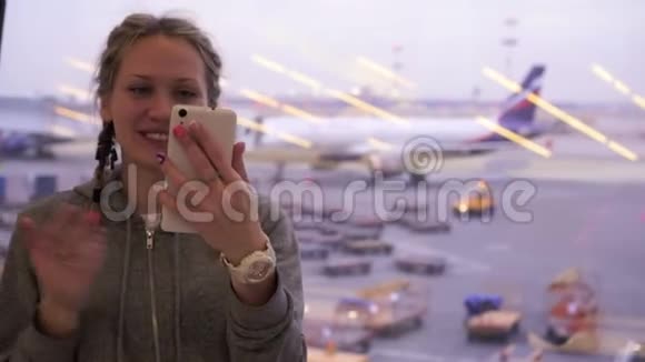 带着智能手机的年轻女游客在机场打视频电话视频的预览图