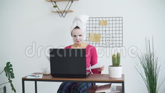 戴面罩的妇女在家工作视频的预览图