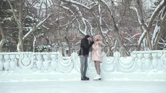 男人在溜冰场上温暖女朋友的手视频的预览图