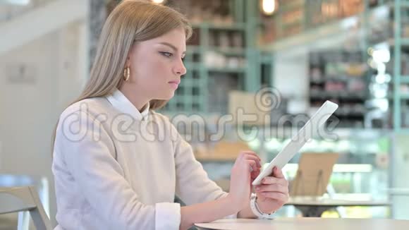 一位在咖啡馆里丢着平板电脑的年轻女子视频的预览图