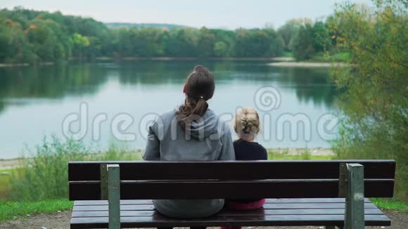 有小女儿的女人欣赏湖景视频的预览图