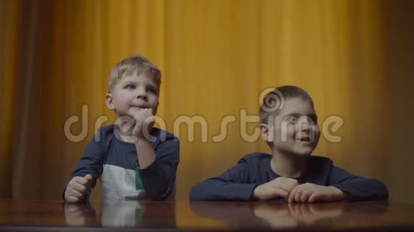 两个兄弟姐妹穿着同样的衣服在家里的桌子上吃着薯片纸袋里的食物男孩喜欢吃零食视频的预览图