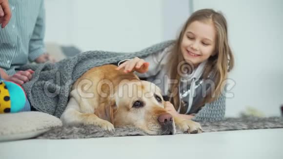快乐女孩踩着狗在家里的地毯上视频的预览图