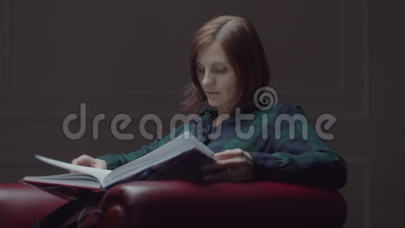 30多岁的年轻女性手牵着手坐在舒适的扶手椅上翻书女人独自坐着看书视频的预览图