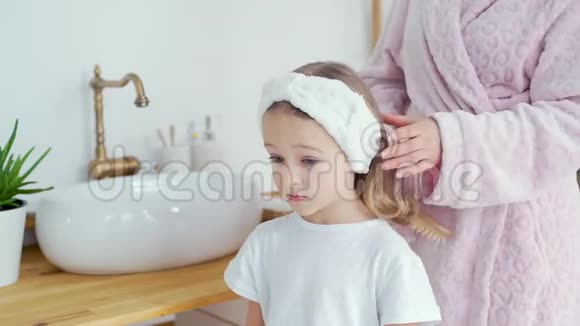 年轻的母亲在家里给女儿梳头视频的预览图