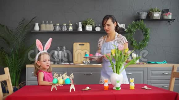 带妈妈的小女孩准备节日复活节餐桌视频的预览图