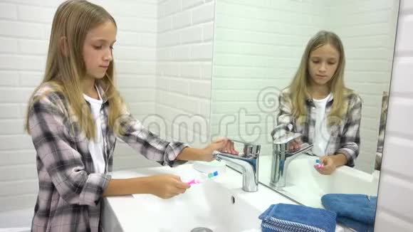 孩子在浴室刷牙孩子用牙刷洗女孩在镜子里视频的预览图