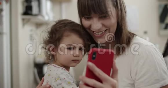 母亲和幼儿在冠状病毒锁定期间与家人保持联系视频的预览图