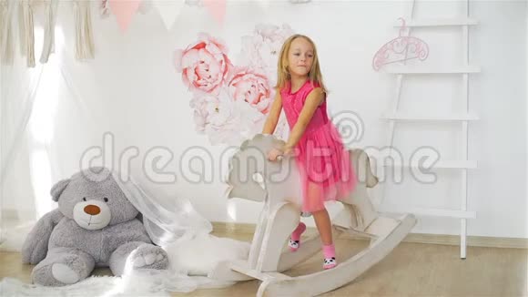 可爱的小女孩骑着玩具摇马视频的预览图