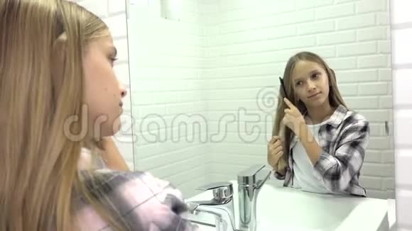 孩子在镜子里梳头孩子在浴室里梳头金发女孩梳头视频的预览图