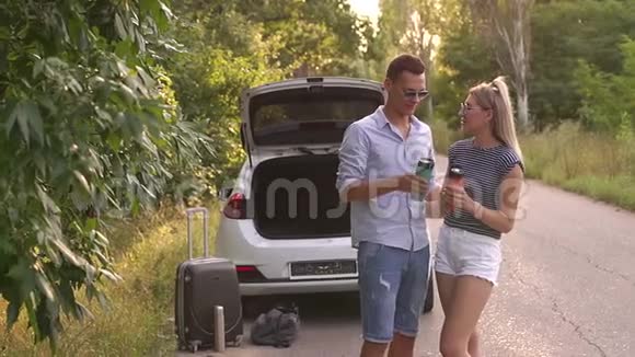 在树林里的路上一对夫妇在汽车附近爱上热杯的肖像视频的预览图