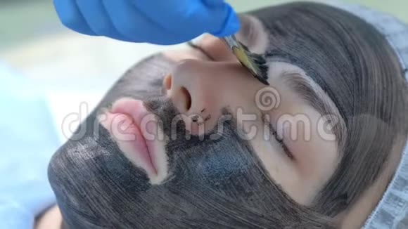 美容师用刷子将碳纳米凝胶涂于女性面部皮肤上视频的预览图