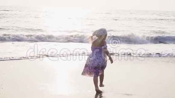 小女孩在大海的背景上奔跑和跳跃晚上慢动作视频的预览图
