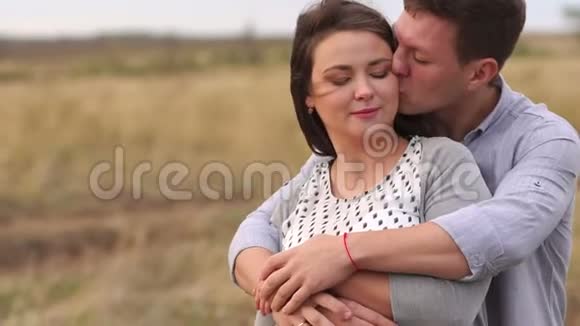 日落时分一位丈夫在田野里温柔地拥抱他怀孕的妻子视频的预览图