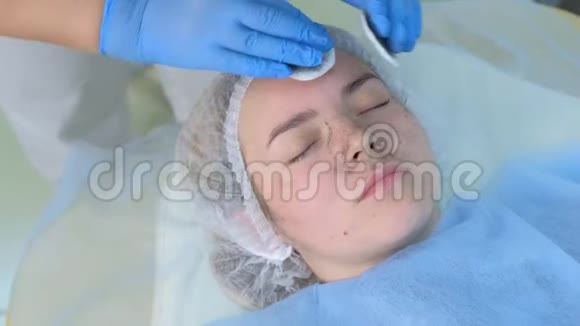 美容师用棉垫擦拭病人女性面部双手特写视频的预览图