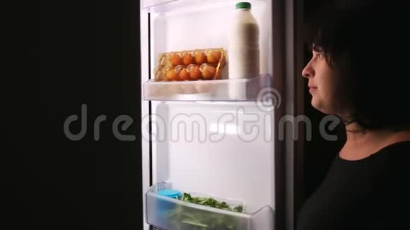 女人晚上在冰箱里吃蛋糕饥饿暴饮暴食饮食视频的预览图