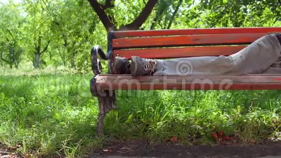 白天在街上的长凳上睡觉的醉汉流浪汉的景色视频的预览图