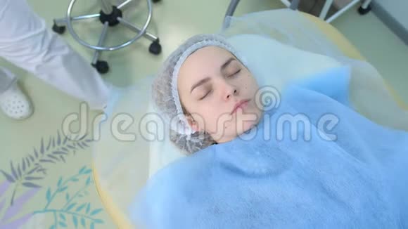 手套美容师正在给客户女性面部按摩皮肤涂霜视频的预览图