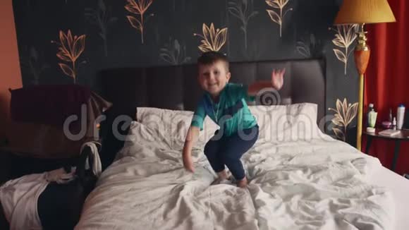 这个男孩在父母的双人床上跳得很高就像在蹦床上一样视频的预览图