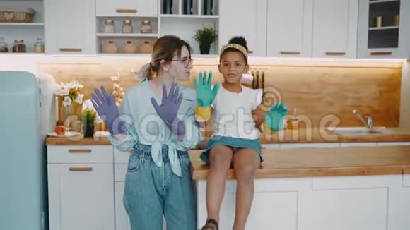 母亲戴着眼镜女儿戴着橡胶手套清洁厨房洗碗保护双手视频的预览图