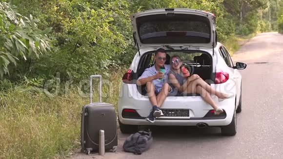 可爱的夫妇喝热茶从热水瓶坐在汽车后备箱视频的预览图