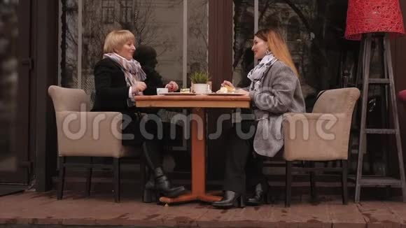 春天一个年老的女人和她成年的女儿在人行道咖啡馆喝咖啡视频的预览图