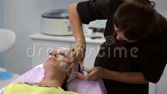 女孩美容师在客户脸上涂一种麻醉霜视频的预览图