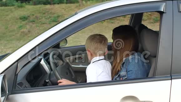 可爱有趣的男孩和他的母亲坐在驾驶座的车里视频的预览图