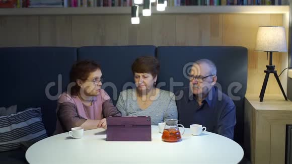 高级朋友小组在桌上观看照片视频的预览图