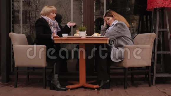 一个成年的女儿在春天的街头咖啡馆里和她年迈的母亲吵架视频的预览图