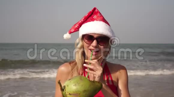 圣诞节穿着红色比基尼和椰子在海滩上的美女视频的预览图