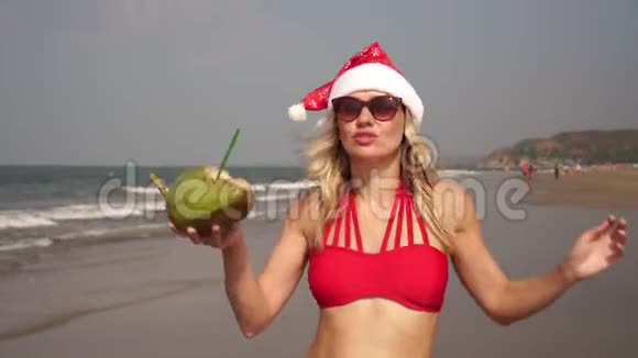 美丽的女人穿着红色比基尼在海滩上跳舞庆祝圣诞节视频的预览图